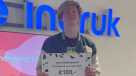 Abel uit Bennekom wint een aanmoedigingsprijs van 100 euro. Hij houdt de cheque vast.