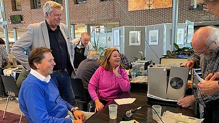 Repair Cafe Raadhuis Rhenen, vrijwilliger repareert een apparaat in bijzijn van de eigenaren..
