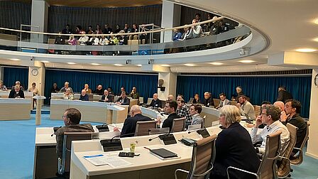 de aanwezigen in de zaal luisteren aandachtig naar de presentatie.