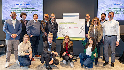 de partners die de samenwerkingsovereenkomst hebben getekend staan voor het bord met handtekeningen.