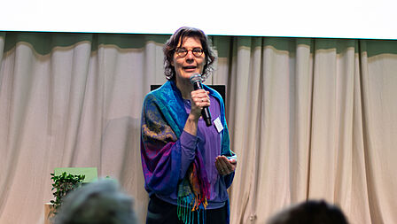 Maud Hulshof staat voor het podium en doet het welkomstwoord.