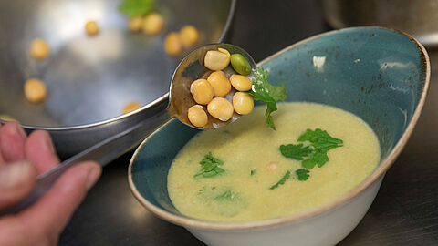 Een kom gevuld met lupine soep, er worden nog losse lupine in de soep gestrooid. 