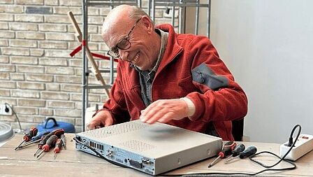 Repair café in Scherpenzeel. Een vrijwilliger maakt een kapot apparaat. 