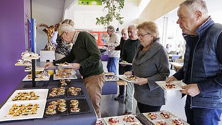 De vrijwilligers lopen langs het buffet met de gerechten gemaakt soor de leerlingen.
