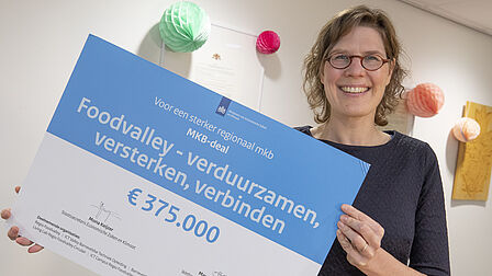 wethouder Maud Hulshof houd de symbolische cheque van € 375.000 vast.