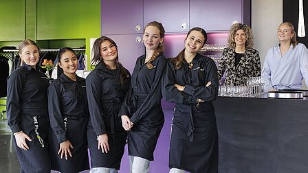 De bediending (leerlingen van de school) staan klaar om de gerechten uit te serveren.