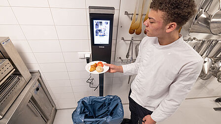 Student van Rijn IJssel Vakschool Wageningen weegt het voedselafval op de Orbisk weegschaal.