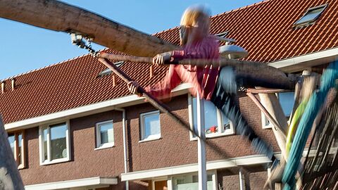 Een woonwijk in Ede. Meisje staat op een schommel in de speeltuin in een woonwijk.